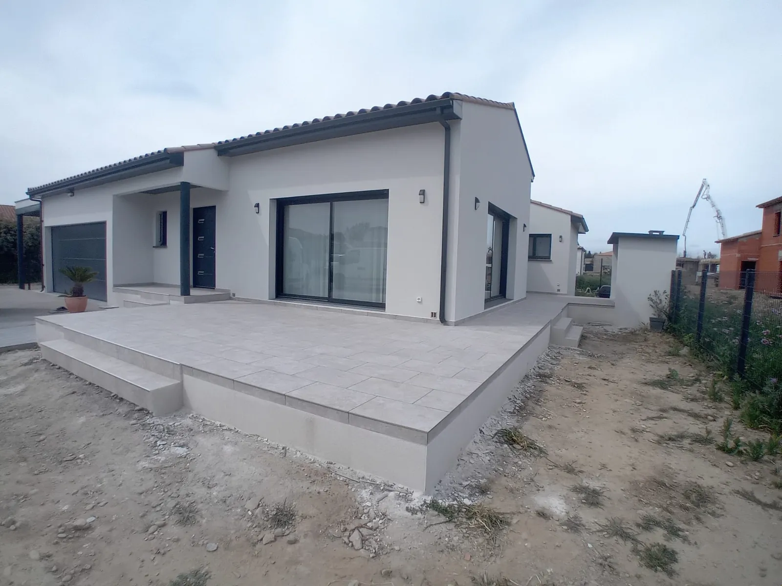 Grande terrasse carrelée devant une maison neuve