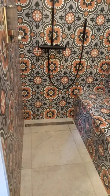 Douche habillée de carreaux de ciment à motifs orange et gris, avec banc carrelé