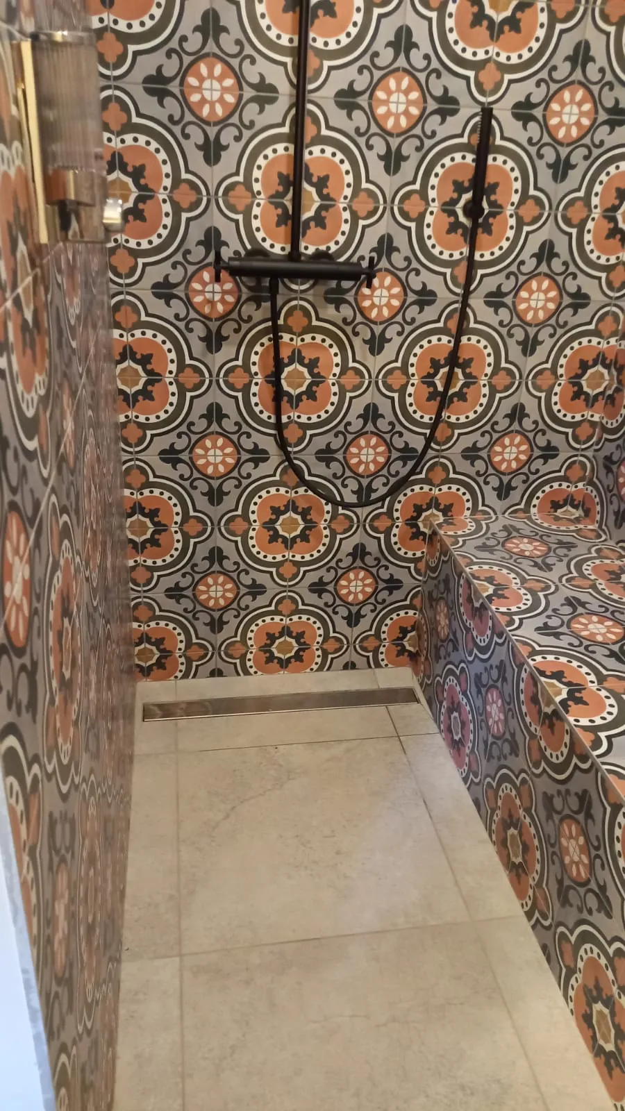 Douche habillée de carreaux de ciment à motifs orange et gris, avec banc carrelé