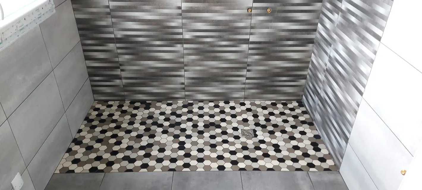 Receveur de douche carrelé en petits hexagones noirs, gris et blancs
