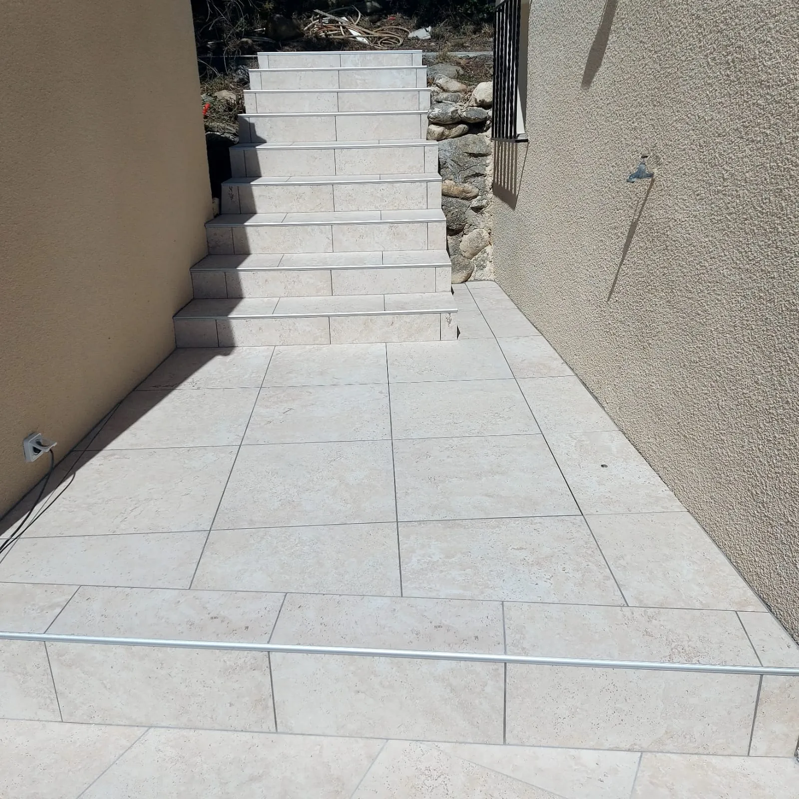 Escalier extérieur et allée carrelés en grès clair le long d'une maison