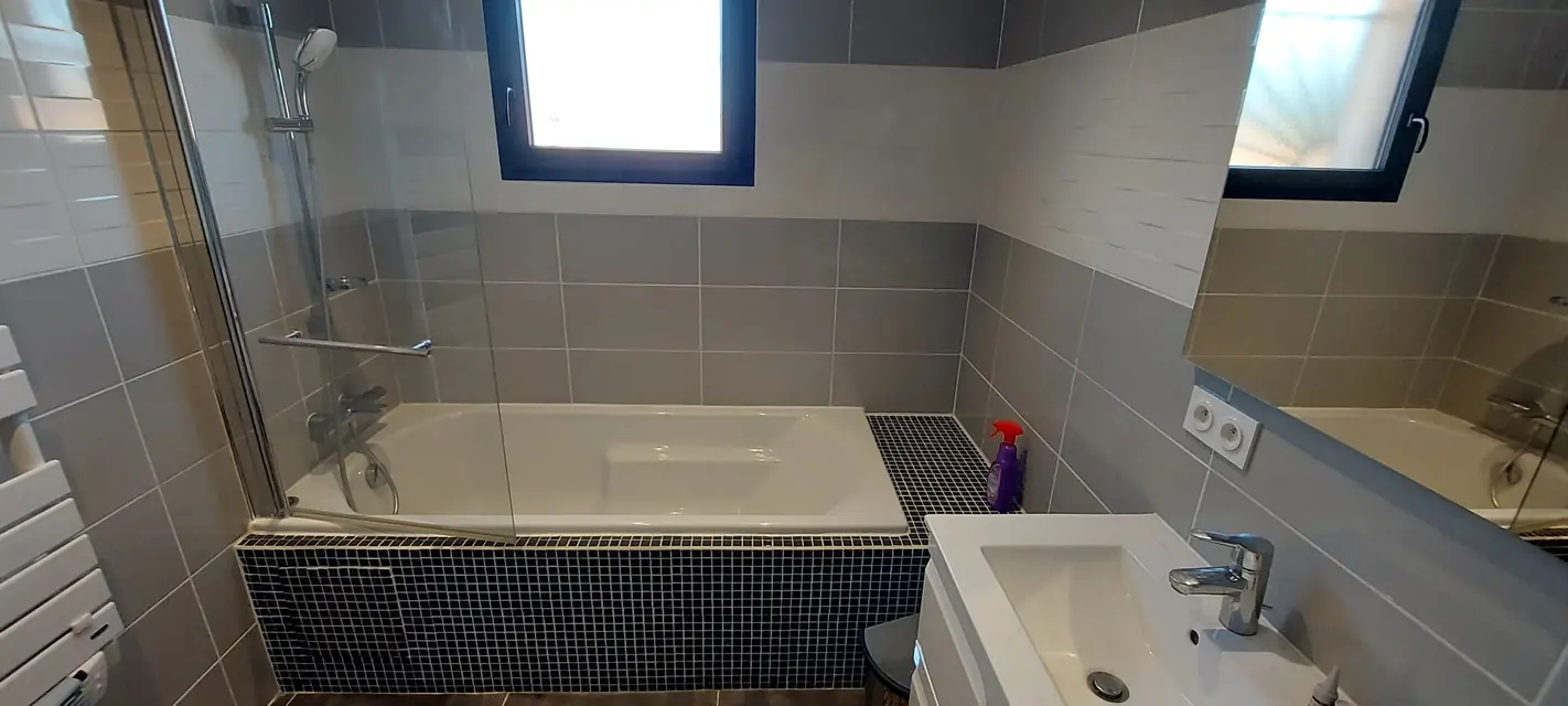 Salle de bain carrelée en gris avec tablier de baignoire en mosaïque noire