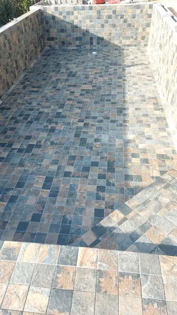 Piscine carrelée en mosaïque effet pierre aux tons bleus et ocre
