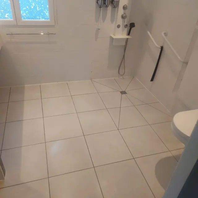 Douche de plain-pied en carrelage blanc grand format avec pentes vers le siphon