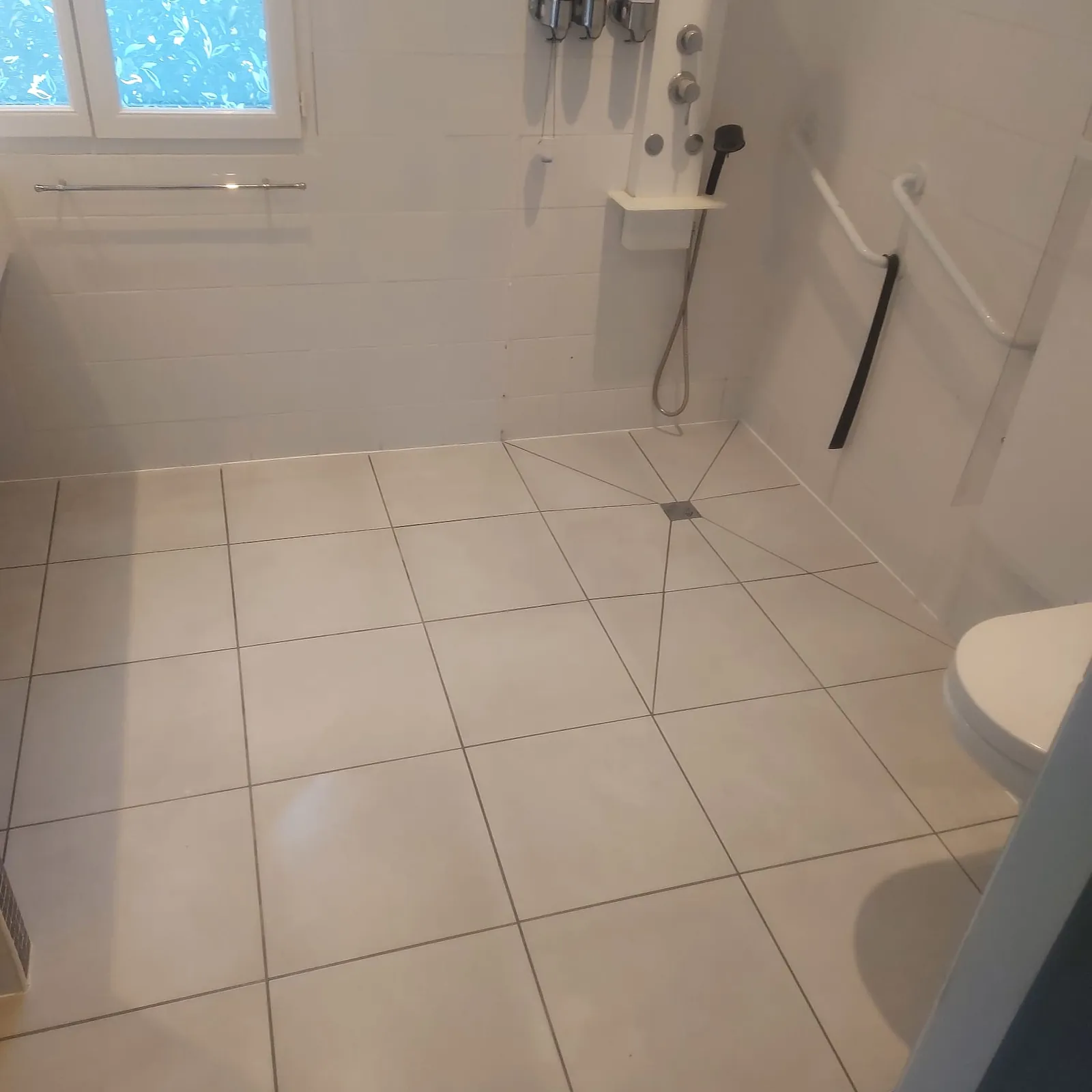 Douche de plain-pied en carrelage blanc grand format avec pentes vers le siphon
