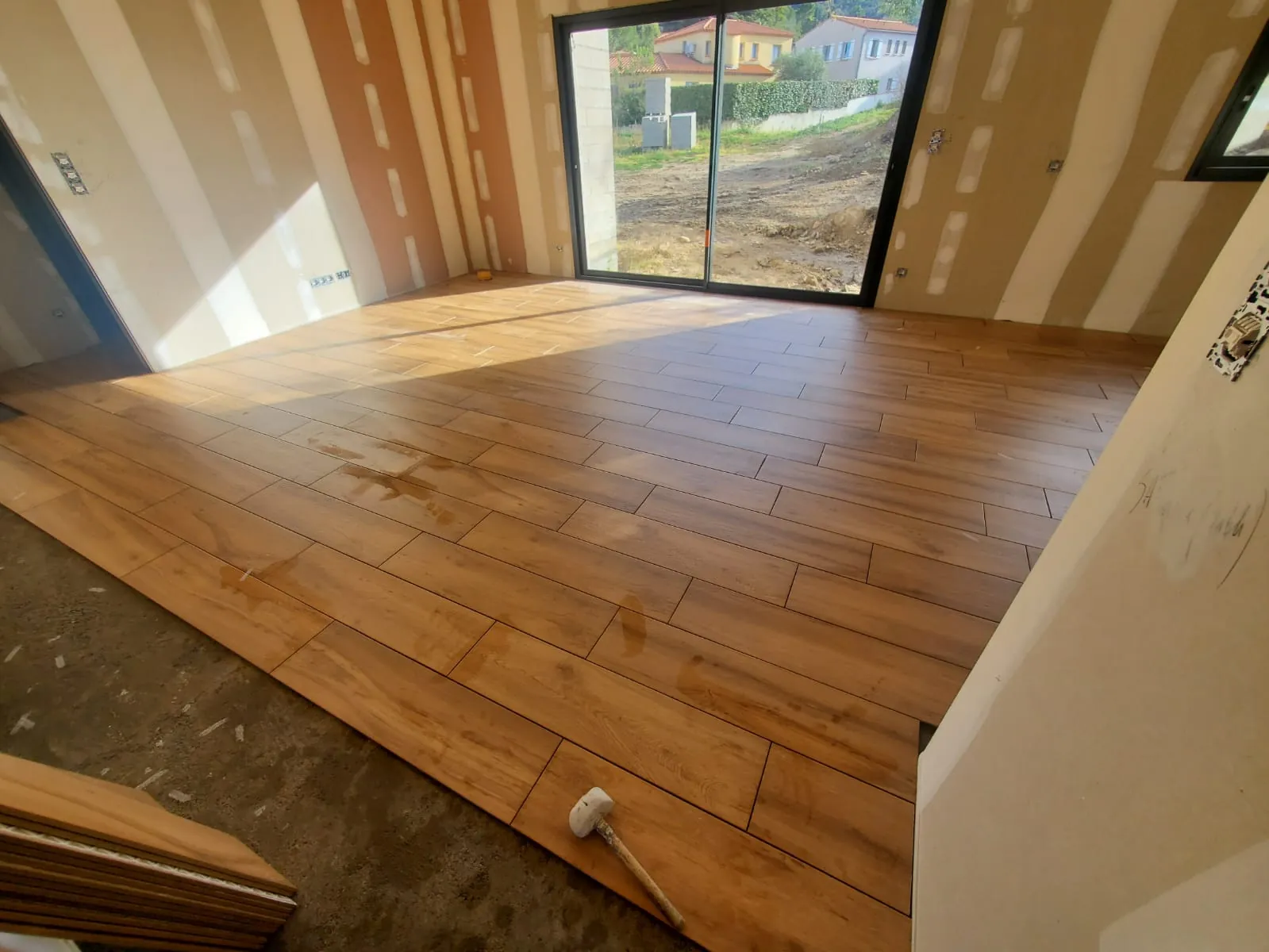 Sol en carrelage imitation parquet en cours de pose dans un séjour