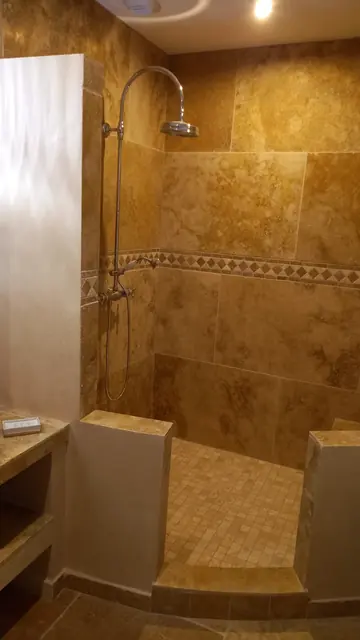 Douche à l'italienne en travertin avec frise décorative